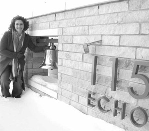 Emily Meyers stands beside 115 Echo’s prominent entrance feature with its restored bell from the now demolished Holy Trinity Church. Photo by John Dance